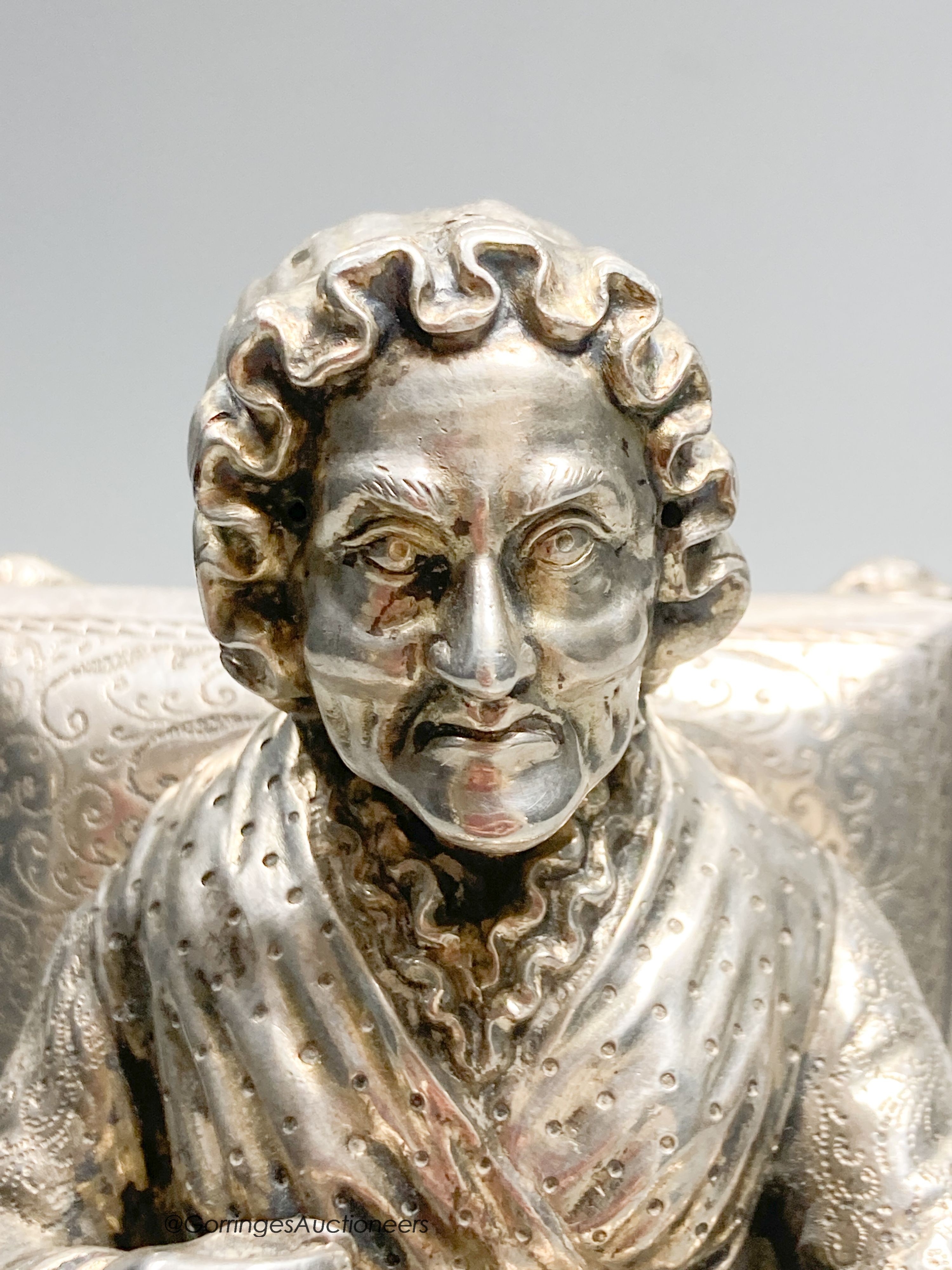 A late 19th century Hanau? white metal miniature model of an elderly lady seated in an armchair with cushion, engraved verso '1553, height 13.5cm